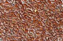 Shiny brown flax seeds, flat and oval, filling the frame