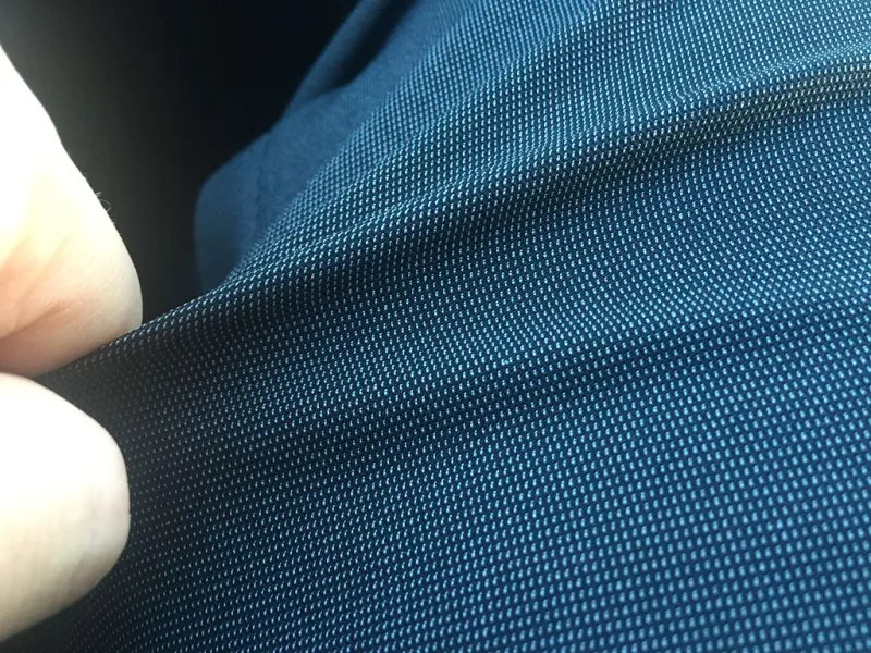 Close-up of a navy blue woven polyester fabric being stretched between two fingers