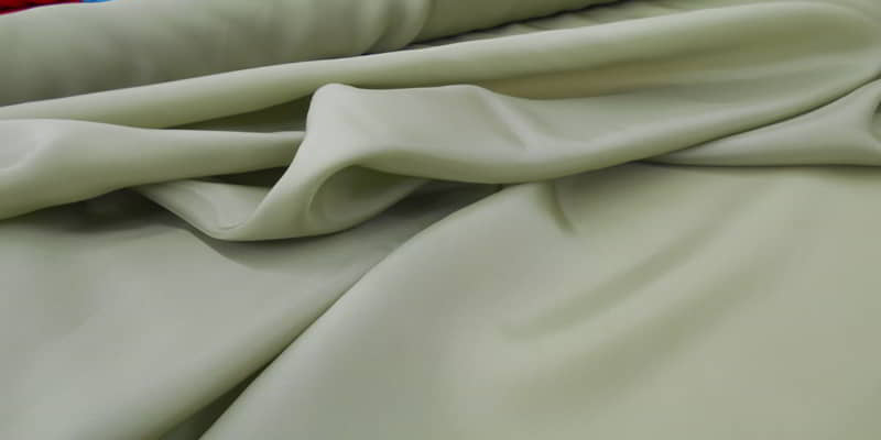 Soft folds of a smooth, pale green woven dress fabric