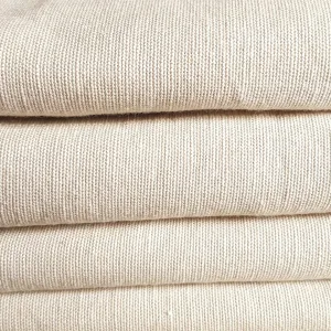 Folded layers of undyed, oatmeal-coloured plain-woven fabric in a stack