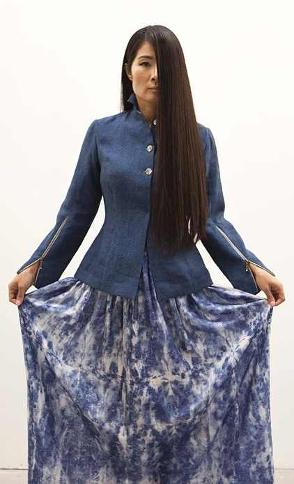 Woman in a fitted indigo-dyed linen jacket and a long blue and white hand-printed silk skirt